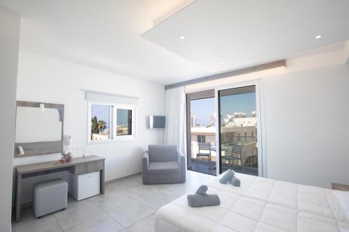 a white bedroom with a bed and a desk and a chair at Pavlinia Hotel & Apartments in Ayia Napa