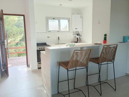 a kitchen with a counter and two bar stools at Village de Mar in Monte Hermoso
