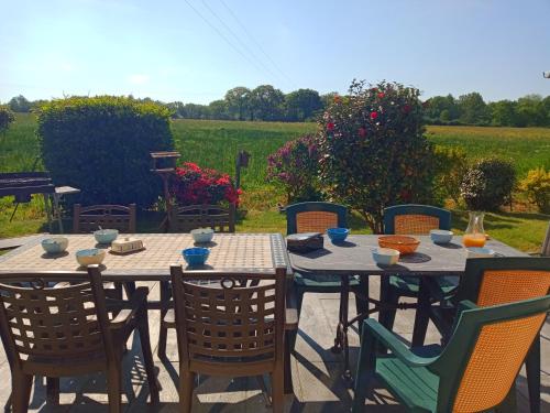 une table en bois avec des chaises et une table avec de la nourriture dans l'établissement GITE la belle échappée, à Jullouville
