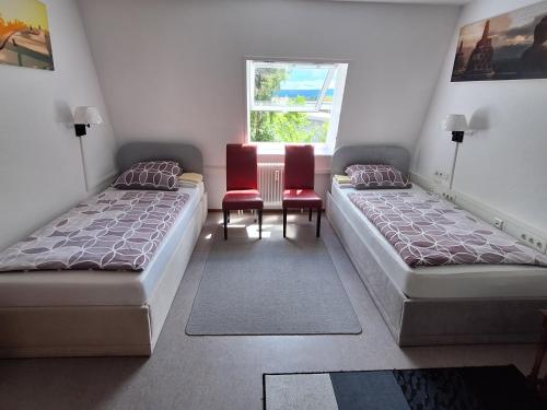 2 Betten in einem Zimmer mit 2 Stühlen und einem Fenster in der Unterkunft Pension beim Kastell in Sulz am Neckar