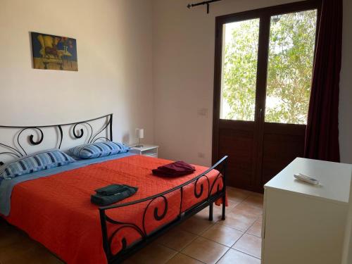 a bedroom with a bed with a red blanket and a window at Punta del Cane in Fontane Bianche