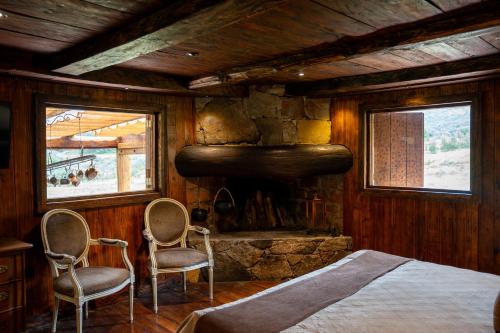 1 dormitorio con 1 cama y 2 sillas frente a una chimenea en Hacienda Hostería Dos Chorreras, en Cuenca