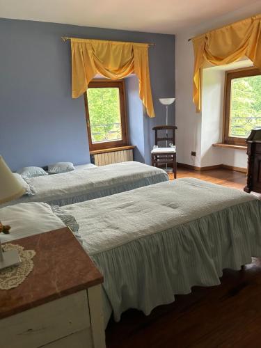 two beds in a room with two windows at Cascina Ciosse B&B in Grognardo