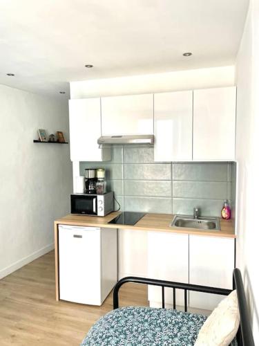 une cuisine avec des armoires blanches et un micro-ondes dans l'établissement Le Nid du Miroir, à Martigues