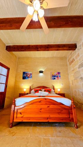 a bedroom with a wooden bed with a ceiling fan at Traditional Farmhouse Central Gozo in Xagħra