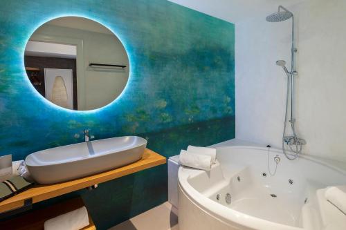 a bathroom with a tub and a sink and a mirror at Hotel Spa Porto Cristo in Port de la Selva