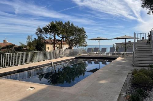 une piscine avec tables et parasols sur un patio dans l'établissement Cap d Antibes Villa contemporaine pied dans l eau, à Antibes