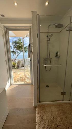 une salle de bain avec une douche avec une porte vitrée dans l'établissement Cap d Antibes Villa contemporaine pied dans l eau, à Antibes