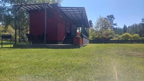 una cabina roja en un campo con césped en Pids randõ, en Kolka