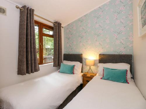 two twin beds in a room with a window at Footprints Lodge in Windermere
