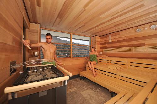 a man and a woman sitting in a sauna at Naturhotel Edelweiss Wagrain in Wagrain
