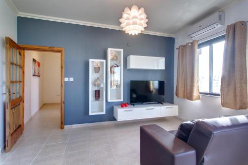 a blue living room with a couch and a tv at Cozy Apartment in St Paul's Bay in St Paul's Bay