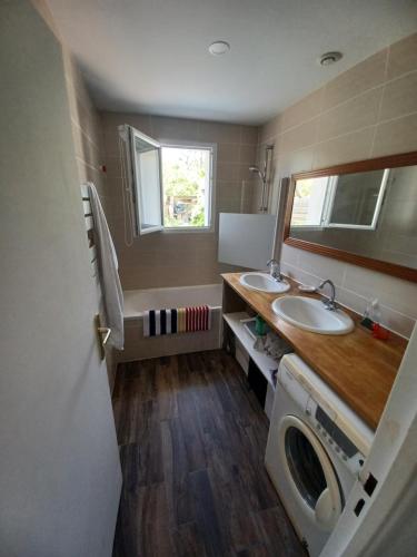 een badkamer met 2 wastafels en een wasmachine bij Maison la LICORNE MARINE à 2 minutes à pied de la plage in Lacanau