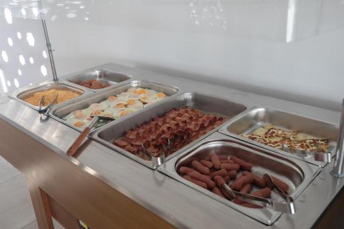 a buffet with three trays of different types of food at Pavlinia Hotel & Apartments in Ayia Napa