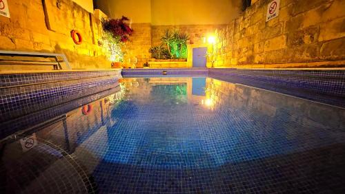 a swimming pool with a tile floor in a building at Traditional Farmhouse Central Gozo in Xagħra