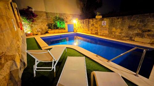 uma piscina com uma cadeira, uma mesa e uma cadeira em Ta Katrin 3 Bedroom Farm House em Xaghra