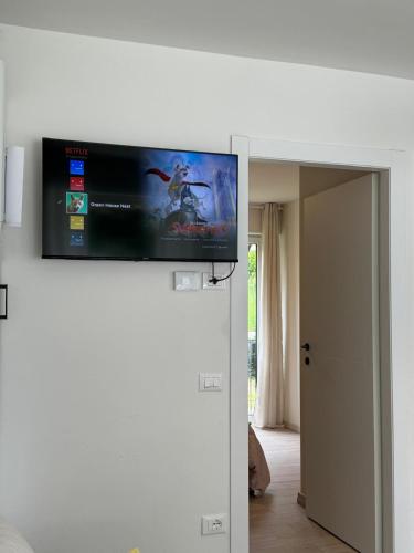 a flat screen tv hanging on a wall at Green House Next - Lovely Apartment for family and Free Parking in Levico Terme