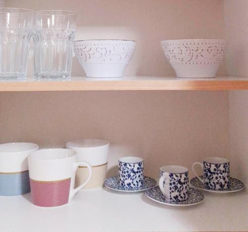 a row of cups and saucers on a shelf at A-Apartments -- Agiou Therapontos in Athens