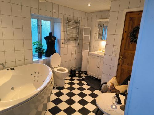 a bathroom with a tub and a toilet and a checkered floor at Luxury Tent with Restroom and shower, close to the Beach in Ystad