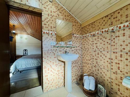uma casa de banho com um lavatório, uma cama e um espelho. em Hospedagem Platô em Monte Verde