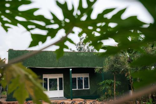 a house with a green roof and white doors at Akagera Bananas Camp in Kabarondo