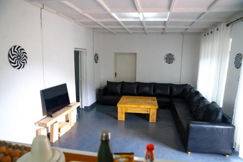 a living room with a black leather couch and a table at Akagera Bananas Camp in Kabarondo