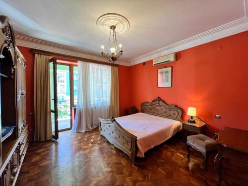 a bedroom with orange walls and a bed and a chandelier at Guesthouse Parnavaz Mepe in Batumi