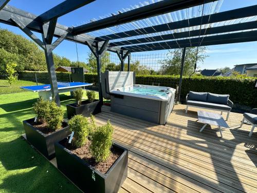 une terrasse avec un bain à remous, une table et un banc dans l'établissement Maison B chaleureuse avec espace SPA et air de jeux, à Yvias