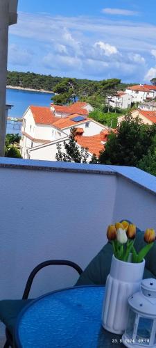a vase of flowers on a table on a balcony at Riviera Rooms and Apartments in Rab