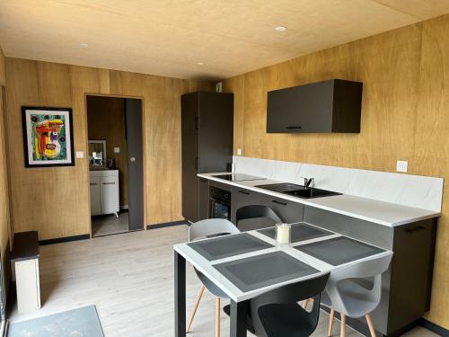 une cuisine avec un évier et une table avec des chaises dans l'établissement Maison B chaleureuse avec espace SPA et air de jeux, à Yvias