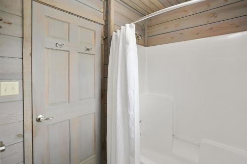a bathroom with a white shower curtain next to a door at Coastawhile by Pristine Properties Vacation Rentals in Indian Pass