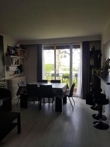 un salon avec une table et des chaises et une fenêtre dans l'établissement Appartement près du lac d'Enghien les bains, à Enghien-les-Bains