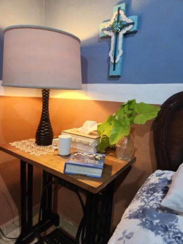 a table with a lamp and a cross on a wall at Campo Paraíso Suites in Mérida