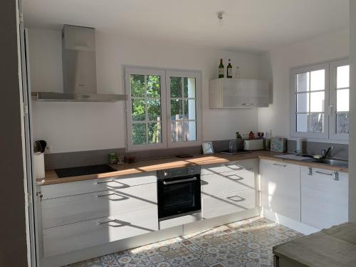 une cuisine avec des armoires blanches et un four à plaques de cuisson dans l'établissement Maison Sarzeau - Port du Logeo - 6-7 personnes, à Sarzeau