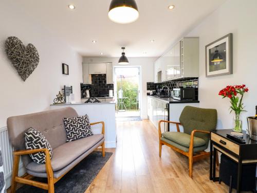 a living room with a couch and chairs and a kitchen at The Den, Bank Top Farm in Ashbourne
