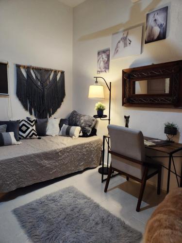 a living room with a bed and a table and a chair at Campo Paraíso Suites in Mérida
