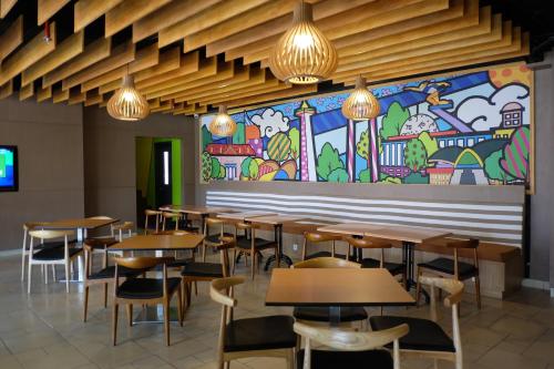 a restaurant with tables and chairs and a mural at MaxOneHotels.com at Pemuda in Jakarta