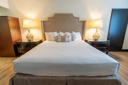a bedroom with a large white bed with two lamps at Sands Inn & Suites in San Luis Obispo