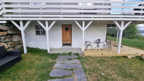 Cette maison blanche dispose d'une terrasse couverte avec une table et des chaises. dans l'établissement Leilighet på Bekkeli, Beito., à Beitostøl