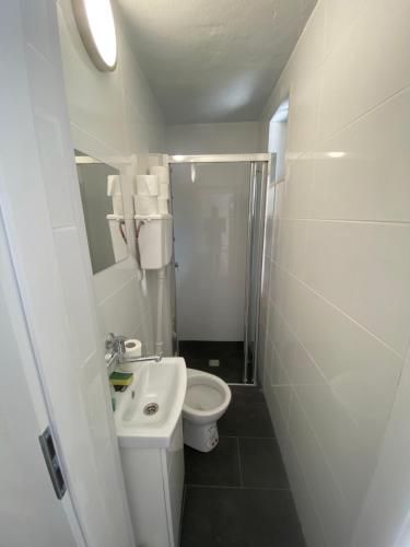 a white bathroom with a toilet and a sink at Domek letniskowy Wielonek 4 in Cierplewo