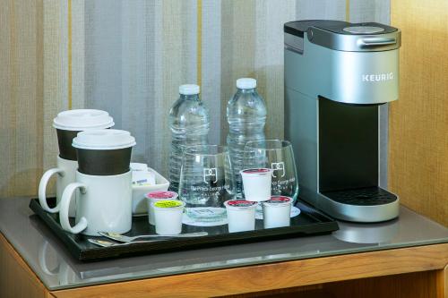 a tray with a coffee maker and cups and water bottles at The Prince George Hotel in Halifax