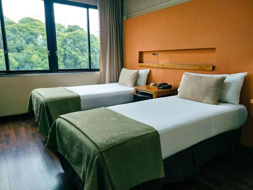 2 camas en una habitación de hotel con ventanas en Hotel Raices Aconcagua en Mendoza