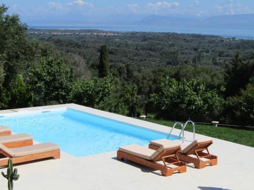 a swimming pool with two lounge chairs and a view at Villa Southern Comfort in Lefkimmi
