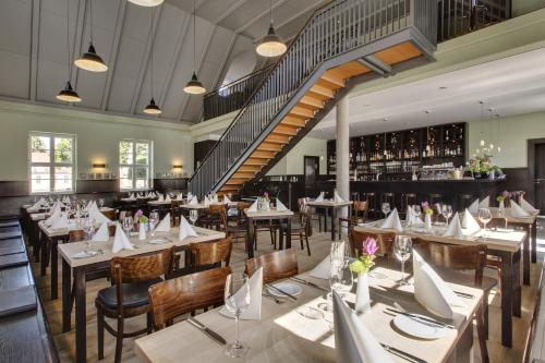 a restaurant with tables and chairs and a staircase at Hotel Schloss Neuhardenberg in Neuhardenberg