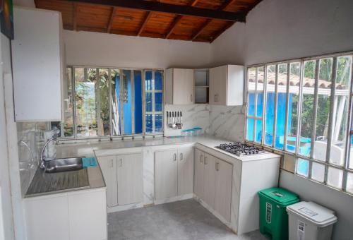 a kitchen with white cabinets and a stove and windows at Finca el Triunfo in Melgar