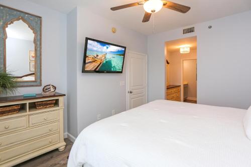 a bedroom with a white bed and a flat screen tv at Waterside Village Condo 304 - Coastal Joy by Pristine Properties Vacation Rentals in Mexico Beach