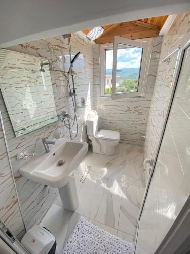 a white bathroom with a sink and a toilet at Guest House Rean in Berat