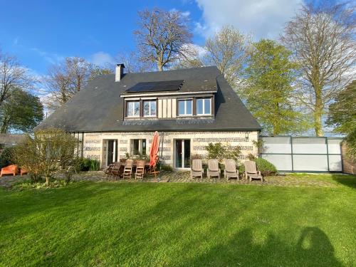 a white house with chairs and a yard at Maison 10p avec piscine, chauffée et partagée avec 1 autre gîte, horaires privatifs pour chaque gîte - Réservation sur https auxportesdetretat fr in Villainville