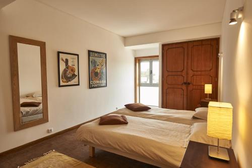 a bedroom with two beds and a mirror at Coimbra Heights in Coimbra