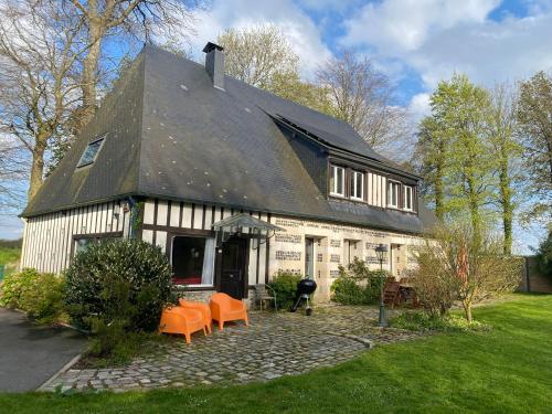 une maison avec des chaises orange devant elle dans l'établissement Maison 10p avec piscine, chauffée et partagée avec 1 autre gîte, horaires privatifs pour chaque gîte - Réservation sur https auxportesdetretat fr, à Villainville